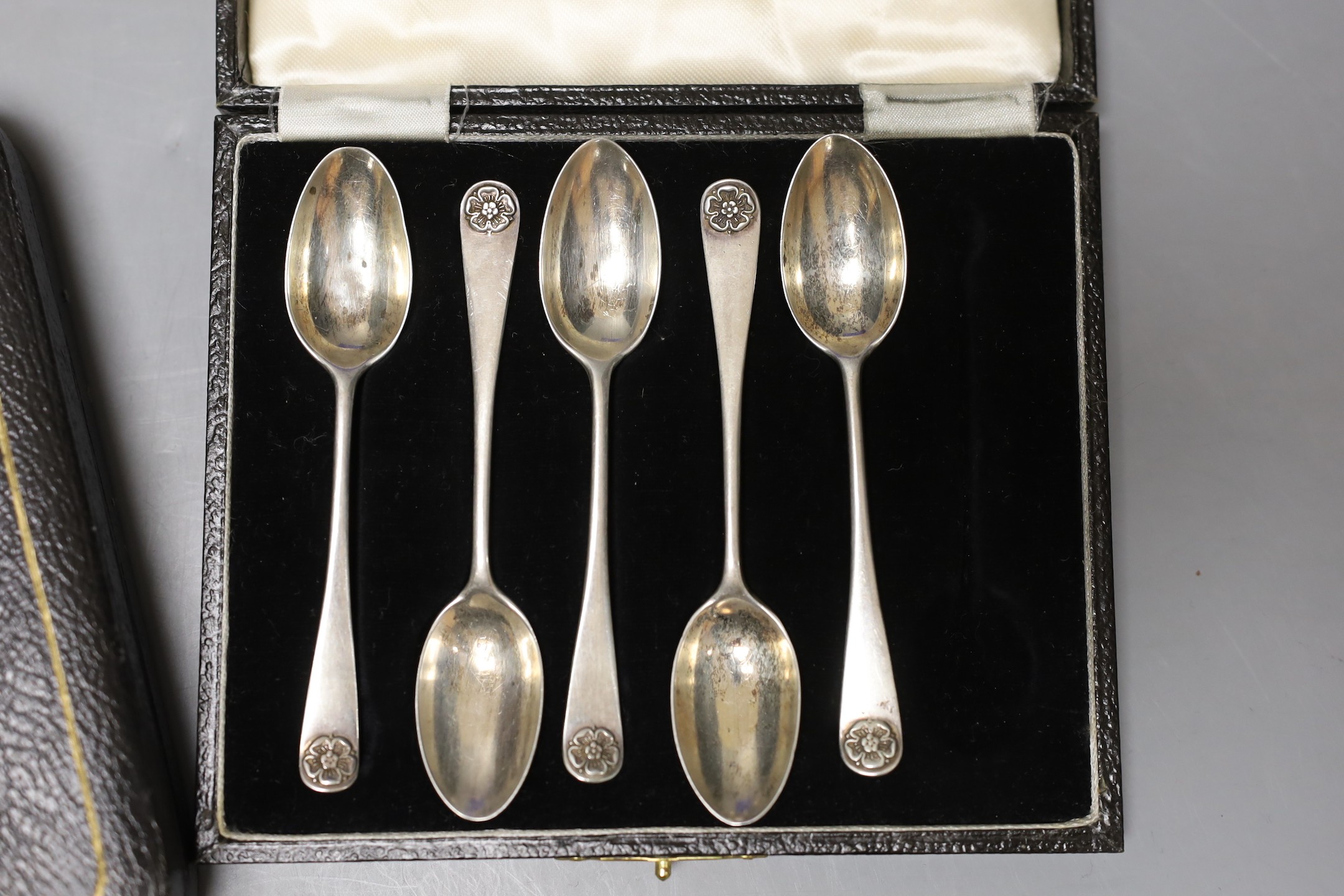 A cased set of twelve Edwardian silver teaspoons with tongs, a cased set of six tea knives and a cased set of 5 (ex 6) silver teaspoons.